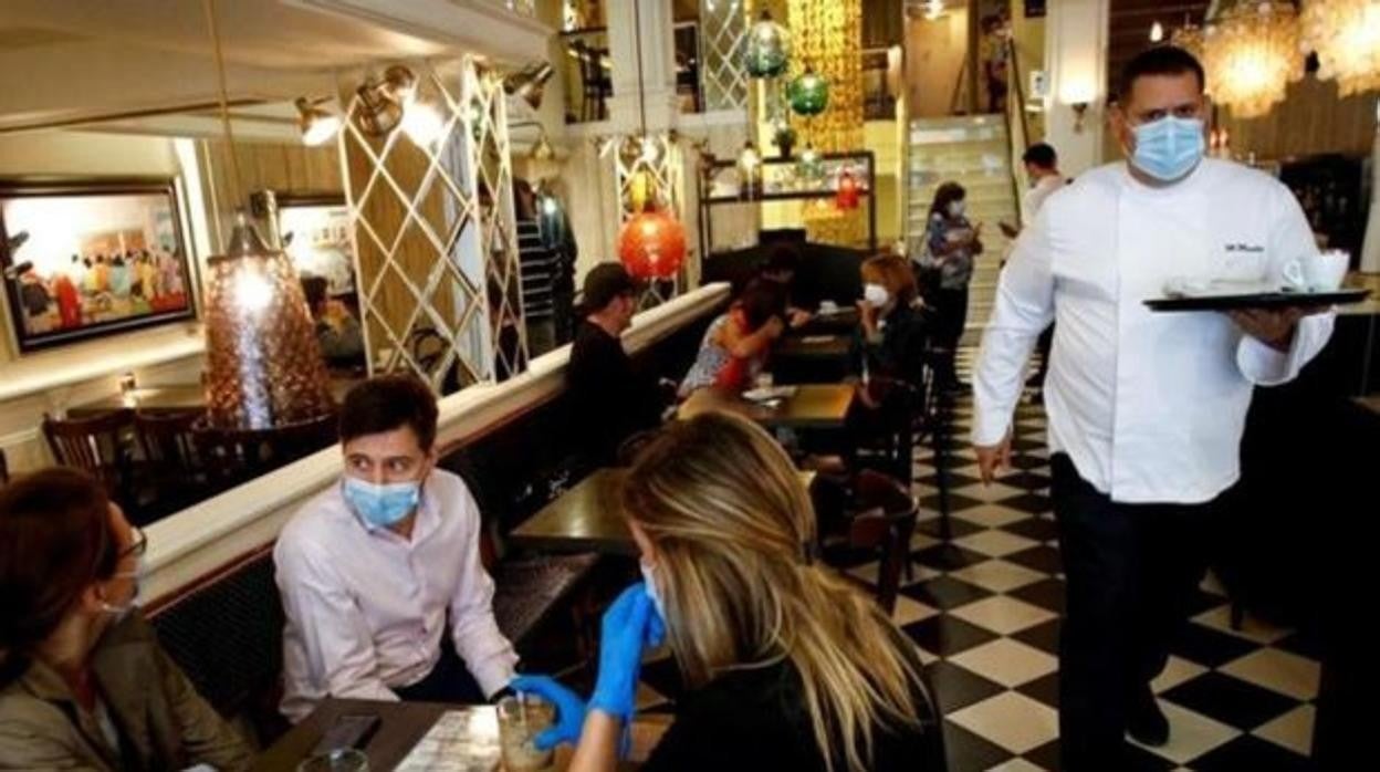 Un bar con clientes con mascarilla en interiores