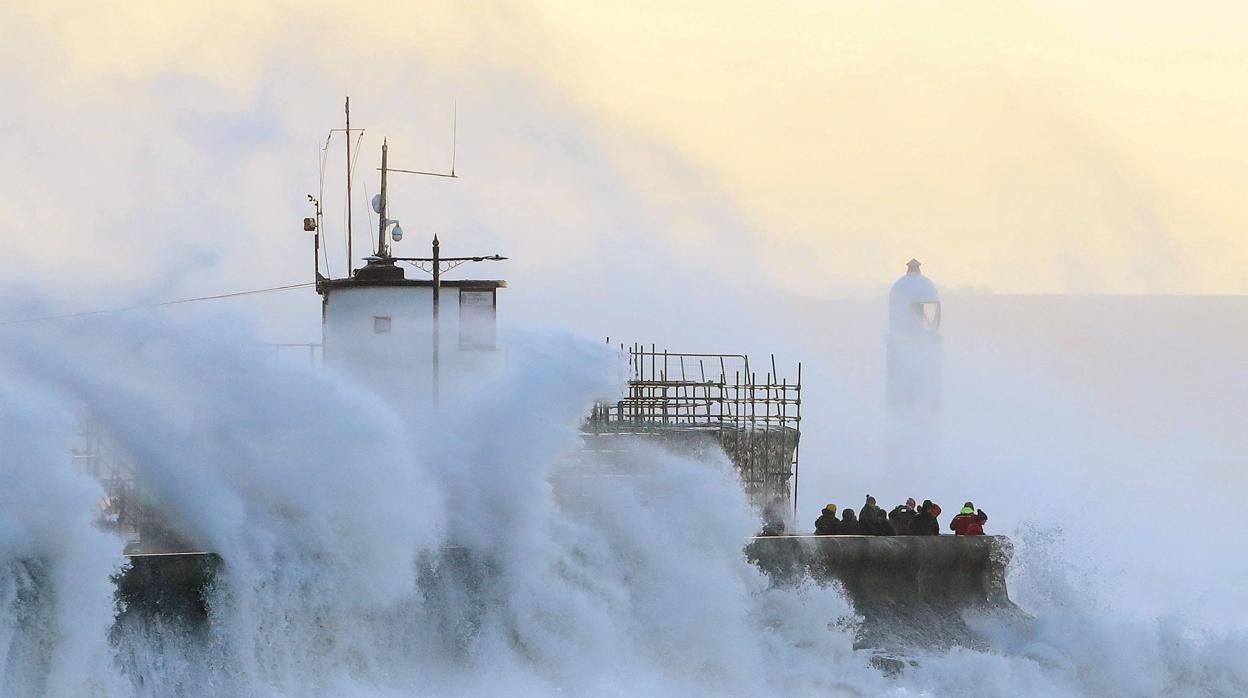 La gente observa cómo las olas chocan contra un muro en Porthcawl, al sur de Gales