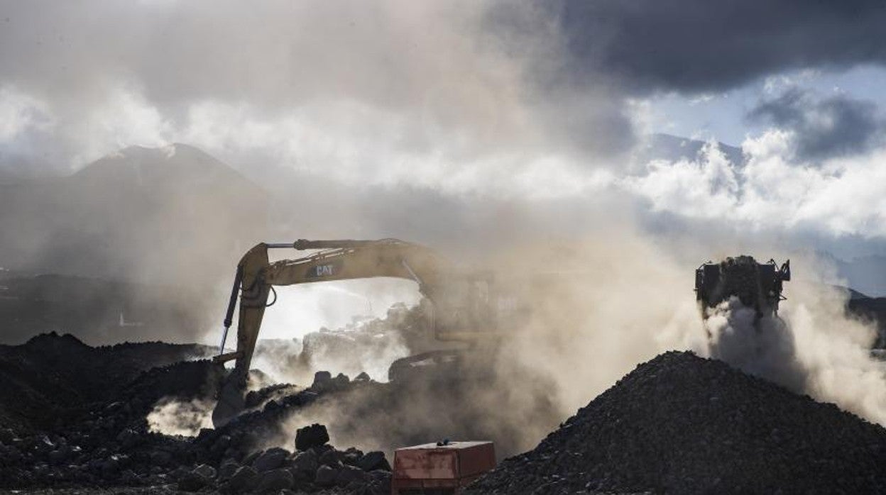 Trabajos en Los Llanos de un operario con una retroexcavadora para romper la lava y abrir camino a las viviendas rehabilitando las carreteras y los servicios esenciales
