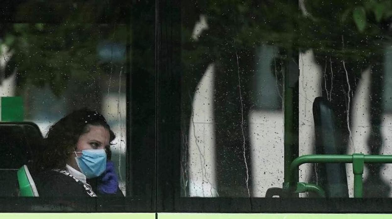 Una mujer viaja en autobús en Córdoba usando mascarilla y guantes