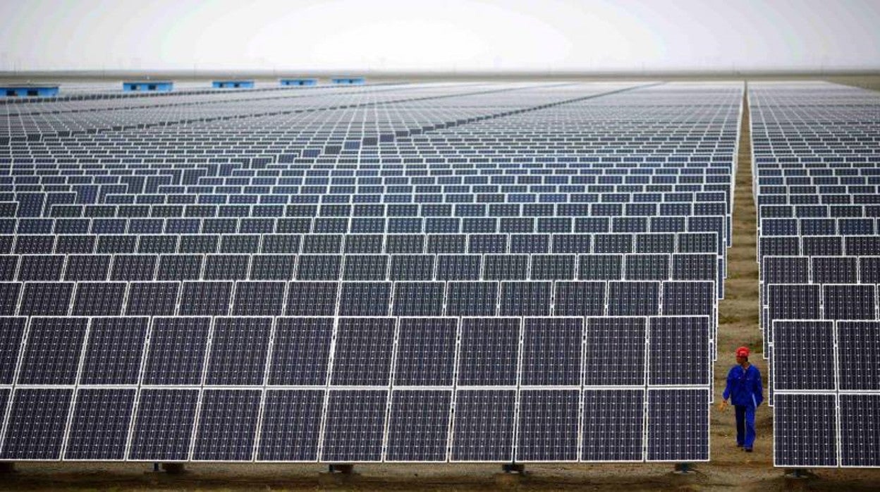 Un trabajador, camina entre los paneles solares de un parque en Dunhuang, China