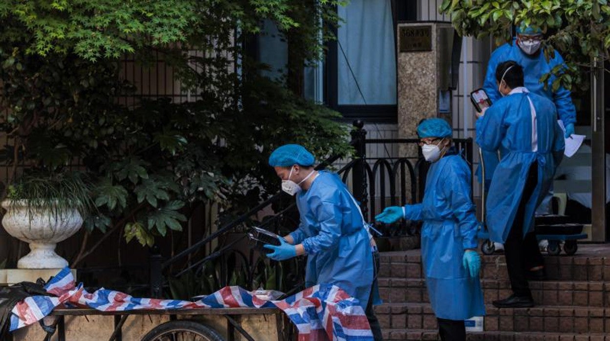 Unos voluntarios reparten raciones de comida a los vecinos confinados en Shanghái (China)