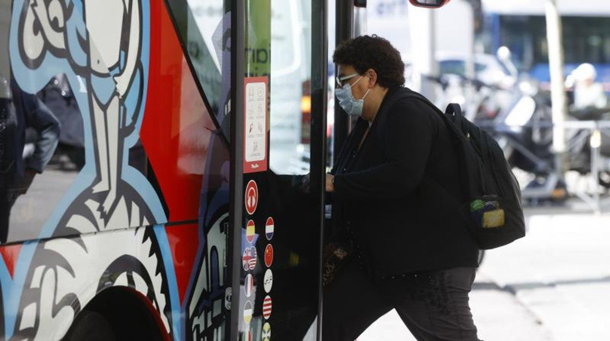 Un hombre con mascarilla sube a un autobús turístico en Madrid