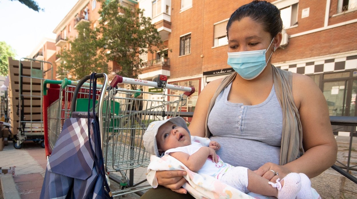 Una madre espera ayuda de Cáritas junto a su bebe