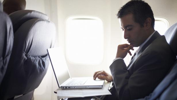 Una persona utiliza su ordenador portátil en un avión