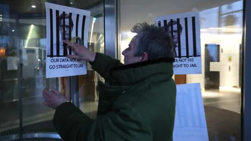 Un hombre pega delante de las oficinas de Cambridge Alnalytica un cartel contra Nix