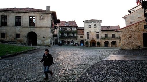 Un niño juega en una plaza de Santillana del Mar en una mañana otoñal