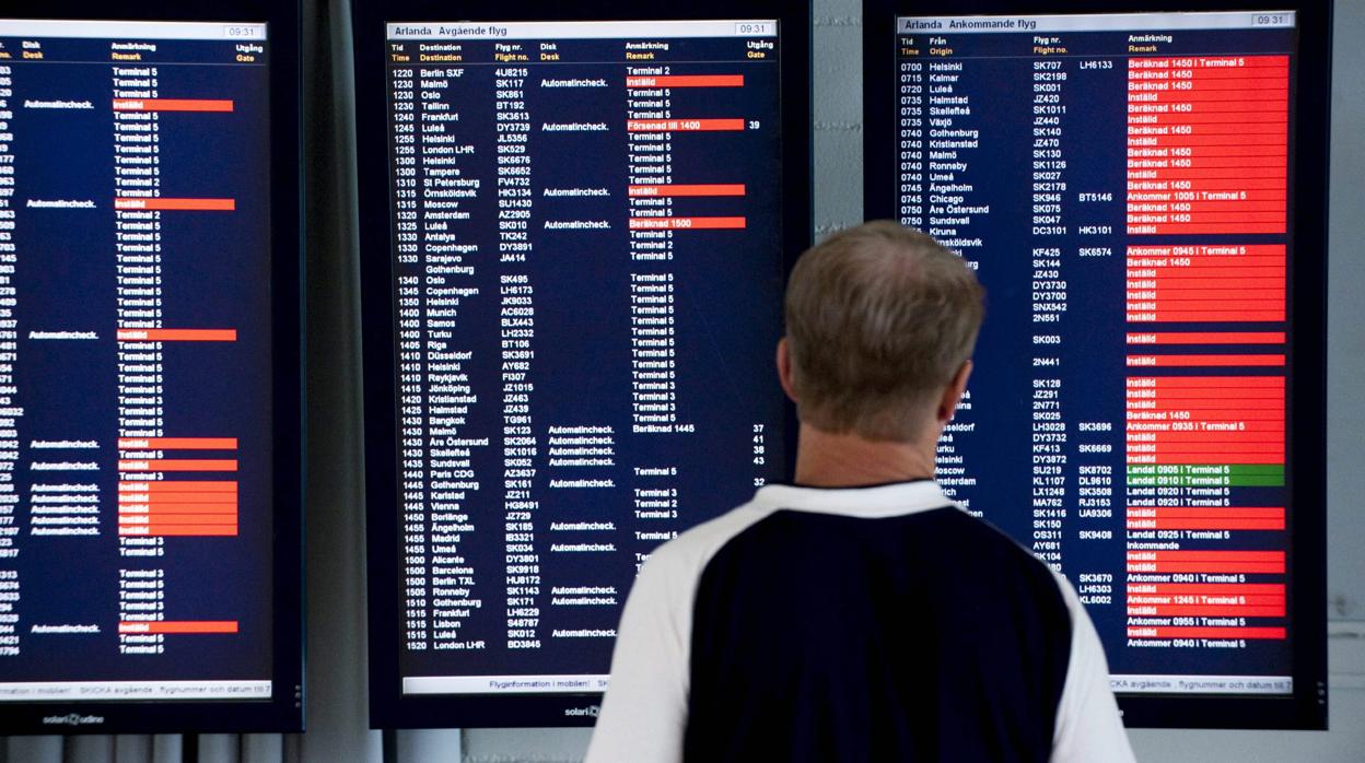 Un pasajero observa el panel deinformación de salidas y llegadas de vuelos en un aeropuerto