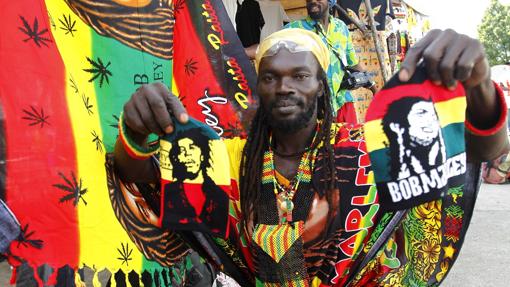 Un miembro del grupo musical Ivoire Binghi muestra banderas con la cara del músico jamaicano Bob Marley en una calle de Abiyán (Costa de Marfil)