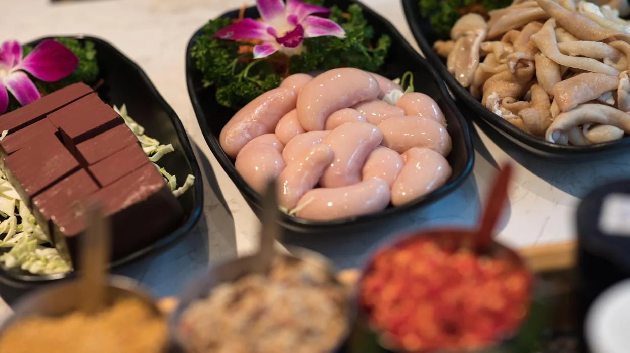 Una fotografía muestra platos de cubos de sangre de pato (izda), testículos de pollo (c) e intestinos de cerdo (dcha) en un restaurante de olla caliente en Hong Kong, China