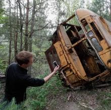 Un hombre toma una fotografía de un autobús abandonado durante una visita guiada a Chernobyl