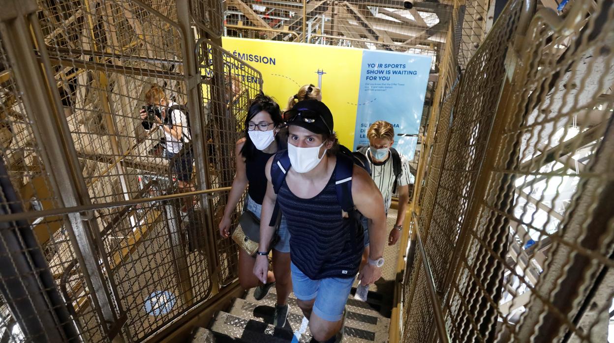 Un grupo de personas con mascarillas sube las escaleras de la Torre Eiffel en París